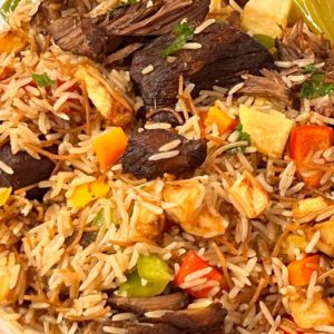 Gros plan sur le RIZ CRÉOLE (250g la part) qui comprend du riz pilaf moelleux avec des morceaux de bœuf, des carottes en dés, des poivrons et une garniture d'herbes fraîches pour un plat coloré et savoureux.