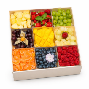 Le coffret COFFRET DE FRUITS FRAIS (Pour 8/10 Pers) comprend neuf sections remplies d'ananas, de fraises, de raisins verts et rouges, de mangues, de raisins blancs, de quartiers de mandarines, de myrtilles et de framboises.