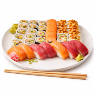 Le PLATEAU SUSHIS PREMIUM se compose d'une assiette blanche avec un assortiment de sushis - saumon et thon nigiri, rouleaux de légumes et de fruits de mer, wasabi, gingembre mariné et baguettes en bois sur le côté.