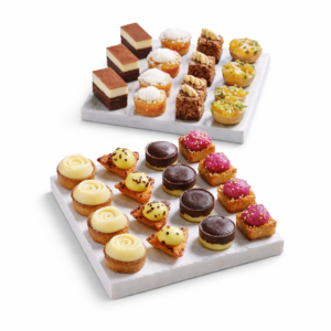 Le PLATEAU DE 48 PETITS FOURS SUCRÉS DÉLICATS présente un assortiment de mini gâteaux, de tartes et de pâtisseries garnies, élégamment présentés sur deux plateaux de marbre blanc sur fond blanc.