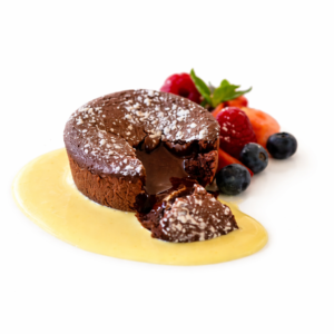 MI CUIT AU CHOCOLAT ET AUX ÉCLATS DE PRALINE ET À LA CRÈME ANGLAISE s'assoit sur une crème anglaise, nappée de sucre en poudre et de baies fraîches, présentée sur un fond blanc.