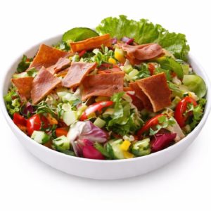 Un bol blanc contient la SALADE FATTOUCHE (Entrée froide - Min de commande 5 parts 150g/Pers), composée de salade verte fraîche, de concombres hachés, de tomates, de maïs jaune et de chips de pita croustillantes.