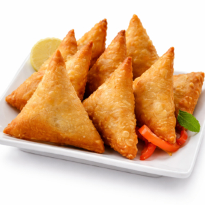 Une assiette blanche avec des SAMOUSSAS AU BOEUF croustillants et dorés (commande 10 pcs minimum), garnis de poivrons rouges en tranches, d'un quartier de citron et d'un brin de menthe, sur fond blanc.