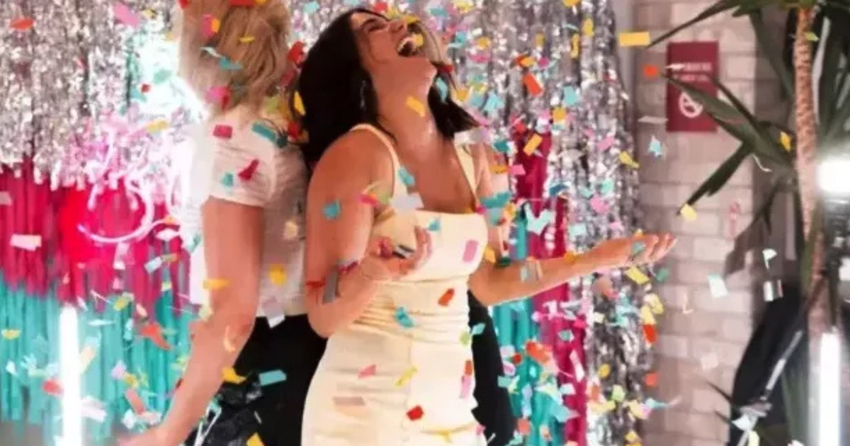 Deux femmes se tiennent dos à dos, souriant et riant tandis que des confettis colorés tombent autour d'elles. L'arrière-plan est décoré de banderoles brillantes et de couleurs festives, créant une atmosphère de fête.