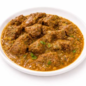 Une portion d'AGNEAU ROGAN JOSH (300 g) présente de tendres morceaux de viande dans une riche sauce au curry brun, garnie d'herbes finement hachées sur une assiette blanche.