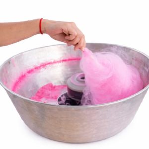 Une main tient un bâton qui fait tourner une barbe à papa rose à l'intérieur de la machine ANIMATION BARBE A PAPA, tandis que des fils de sucre rose se forment autour du centre de rotation.