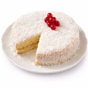 Le BLANC MANGER COCO (Gâteau de 10 parts) est un gâteau rond blanc à la noix de coco auquel il manque une tranche, garni de baies rouges et présenté sur une assiette blanche sur fond blanc.