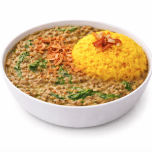 Un bol de DAAL PALAK (250g) - curry de lentilles crémeux avec épinards et oignons croustillants - servi avec du riz jaune safrané garni d'oignons frits.
