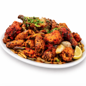 Assiette blanche avec MIX GRILLES (400g) ailes de poulet et légumes grillés et assaisonnés, garnis d'herbes fraîches et de quartiers de citron, sur fond blanc uni.