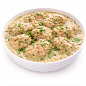 Un bol de MURG MALAI TIKKA (300 g) : des morceaux de poulet marinés aux herbes et à la crème, garnis de coriandre ou de persil frais, servis sur fond blanc.
