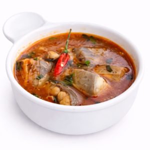 Un bol de PÉPÉ SOUPE (300 g) rempli d'un ragoût de poisson épicé, composé de morceaux de poisson, d'herbes hachées et d'un piment rouge entier dans un bouillon riche et rougeâtre.