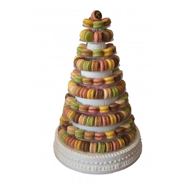 La PIÉCE MONTÉE PYRAMIDE DE 191 MACARONS est une haute tour en forme de cône qui présente des macarons colorés de couleur verte, jaune, rose, marron et beige, empilés avec art sur des gradins circulaires sur une base décorative blanche.