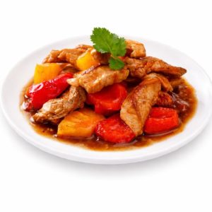Une assiette blanche de PORC SAUCE AIGRE DOUCE (250g/pers) contient de la viande sautée, des poivrons rouges et jaunes, des tranches de tomates et de l'ananas dans une sauce brune, garnie de coriandre.