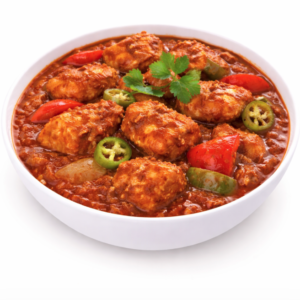 Un bol blanc rempli de POULET VINDALOO (300g) - curry de poulet épicé dans une sauce rouge riche, garni de coriandre, de tranches de piments verts, de morceaux de poivrons rouges et d'oignons.