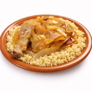 Le POULET YASSA (300 g), un plat savoureux composé d'un couscous accompagné d'un pilon de poulet cuit et d'un ragoût de légumes et d'oignons, est présenté dans une assiette en terre cuite sur fond blanc.