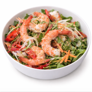 Un bol blanc de SALADE AUX CREVETTES (200g) rempli de grosses crevettes, de tranches de poivrons rouges, de carottes, de légumes à feuilles vertes et de graines de sésame se trouve sur un fond blanc.