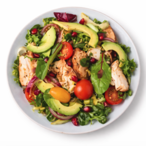 SALAD DE POULET (200g/Pers) : Une salade composée de poulet grillé, de tranches d'avocat, de tomates cerises, d'oignons rouges, de légumes verts mélangés et de graines de grenade sur un fond blanc.